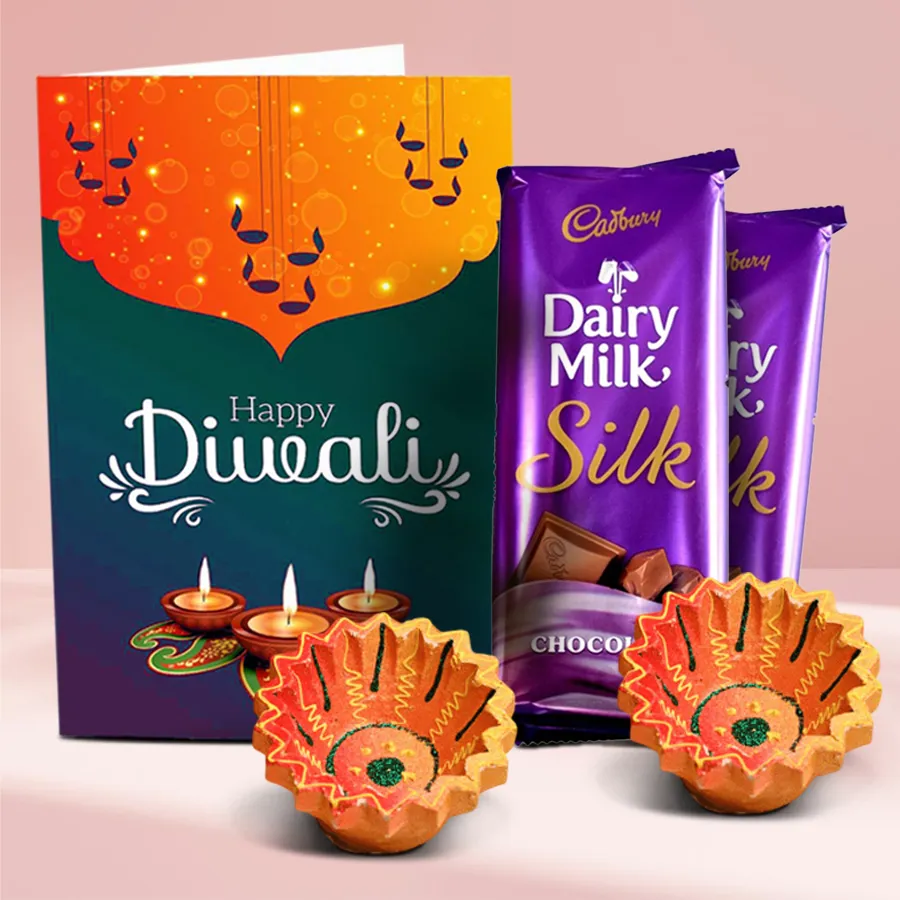 Magical Diwali Gift Box featuring two Cadbury Dairy Milk Silk chocolates, two handcrafted clay diyas, and a Happy Diwali card, all beautifully arranged in a festive presentation.