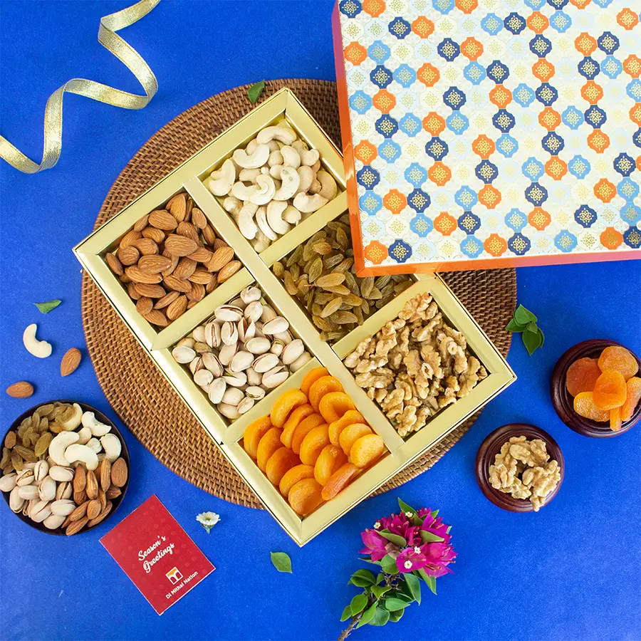 Elegant gift box filled with assorted dry fruits including cashews, almonds, pistachios, apricots, walnuts, and raisins, accompanied by a festive greeting card.