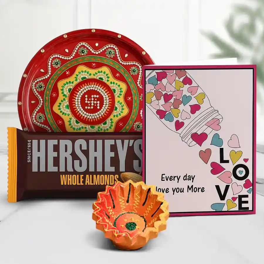 Festive Diwali hamper featuring a diya, Hershey's Whole Almonds Chocolates, an elegant round designer thali, and a personalized message card.