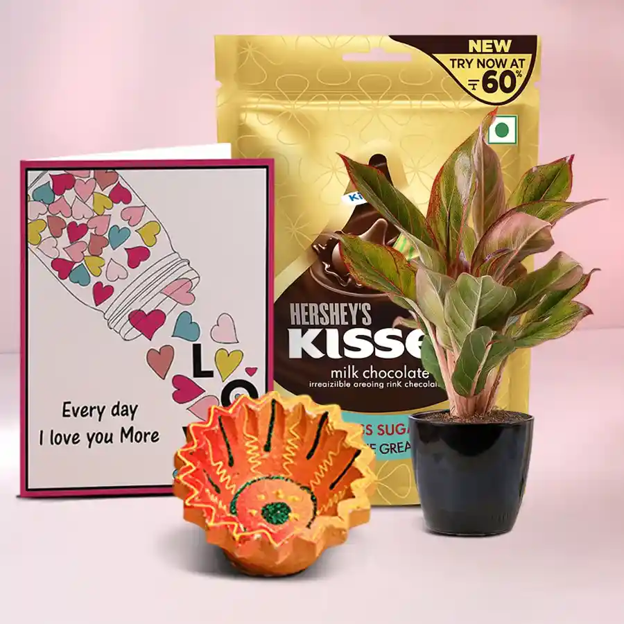 Diwali Joy With Plant Surprise Hamper featuring a traditional Diya, a pack of Hershey’s Kisses Chocolates, and an Aglaonema Lipstick Plant with a free message card