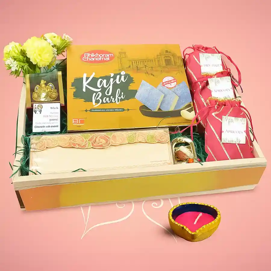 Nuts, Sweets and Diya Delight hamper featuring a Diya, Vignesh Ganesh idol, Kaju Barfi, apricots, dry figs, and pistachios arranged for Diwali celebration.