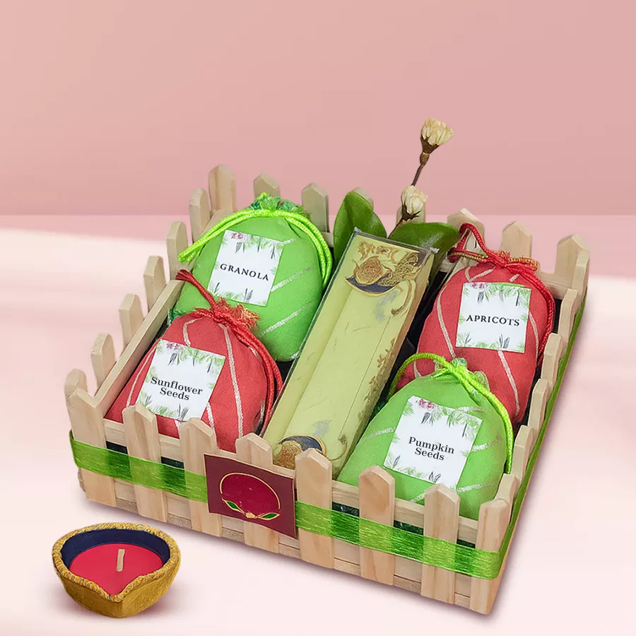 Diwali Wellness Diya and Superfoods Hamper featuring a decorative diya, sunflower and pumpkin seeds, wholesome granola, and dried apricots arranged together.