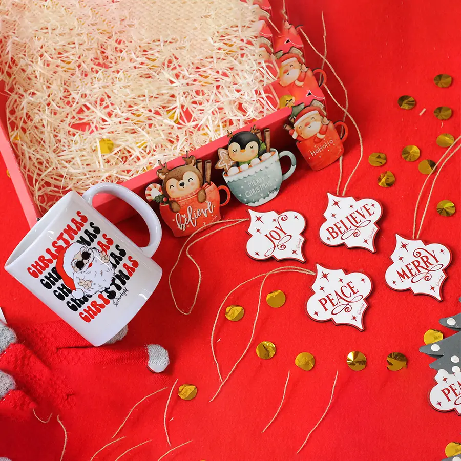 A cozy holiday mug, three festive fridge magnets, and four sparkling Christmas tree ornaments arranged together, showcasing the Perfect Holiday Cheer Collection.