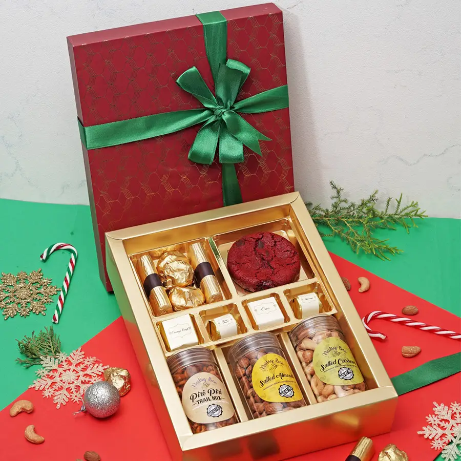 Joyful Christmas Collections Gift Box featuring Red Velvet Cookie, Strawberry Chocolate Logs, Almond Chocolate Rocks, assorted chocolates, Piri Piri Trail Mix, Salted Almonds, and Cashews.