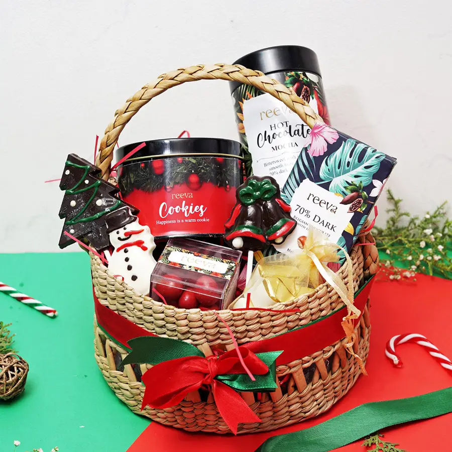 Festive Feast Gift Collection hamper featuring hot chocolate, dark chocolate with hazelnuts, Christmas lollipops, a snowman figurine, assorted chocolates, salted cranberry dragees, and cookies.