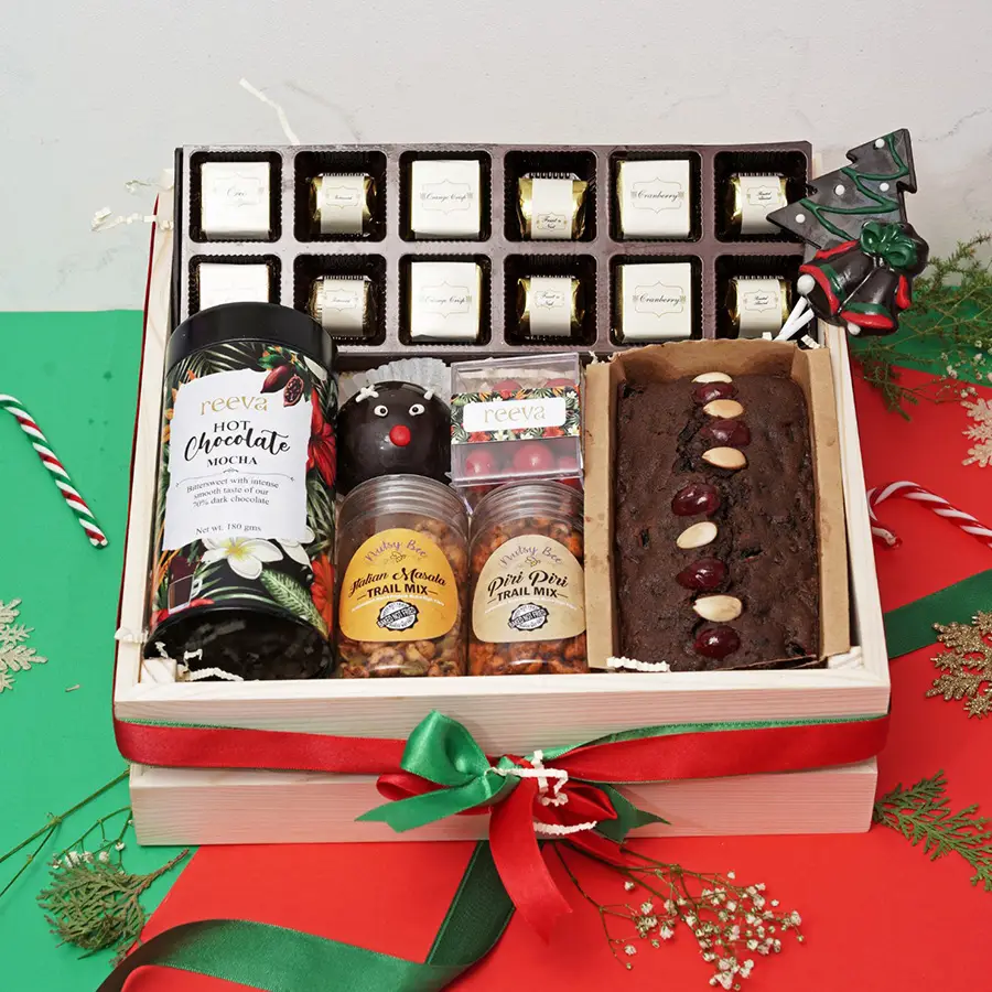 Delectable Assorted Christmas Treats Hamper featuring a variety of festive goodies including chocolates, hot chocolate, trail mixes, a plum cake, and chocolate lollipops.