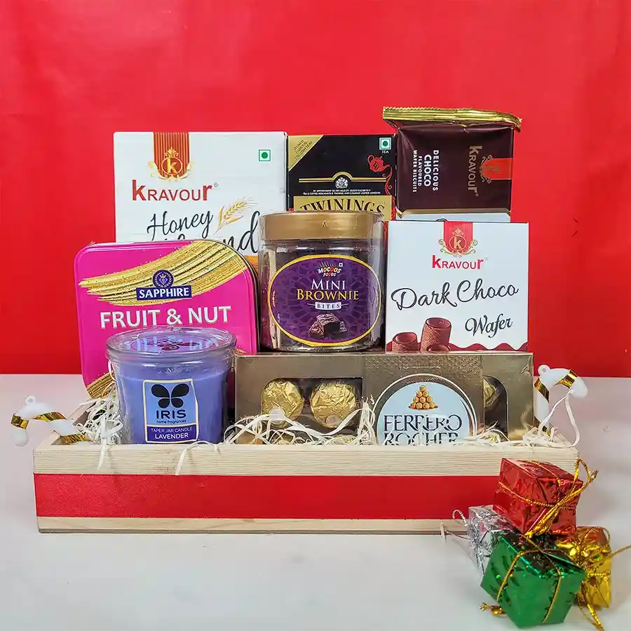 A beautifully arranged Christmas Tea Time Delights Basket filled with Twinings English Breakfast Tea, Ferrero Rocher chocolates, mini brownies, ChocoWafer rolls, honey almond cookies, dark choco wafers, and a cozy IRIS jar candle, all decorated with festive ornaments.