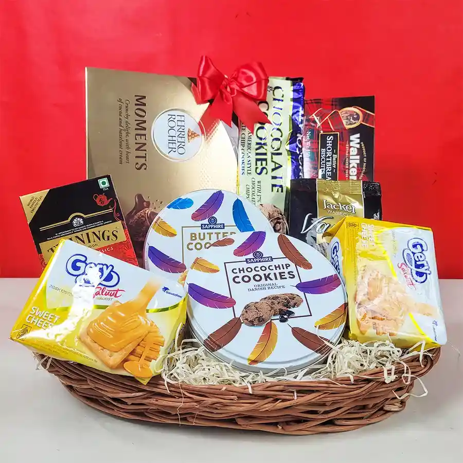 A beautifully arranged Christmas gift hamper filled with gourmet treats including cookies, chocolates, tea, and crackers, all presented in an elegant basket.