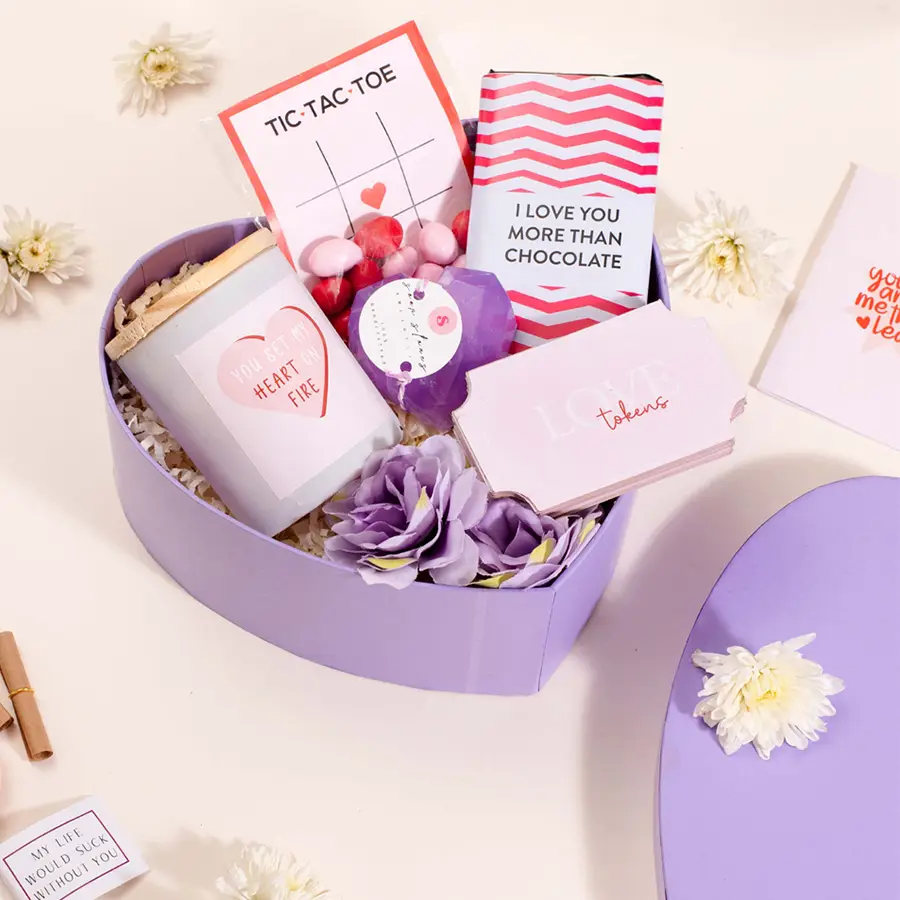 Heartwarming Surprises gift hamper featuring a candle, dragees, chocolate bar, amethyst heart soap, love tokens, and heart-shaped confetti box.