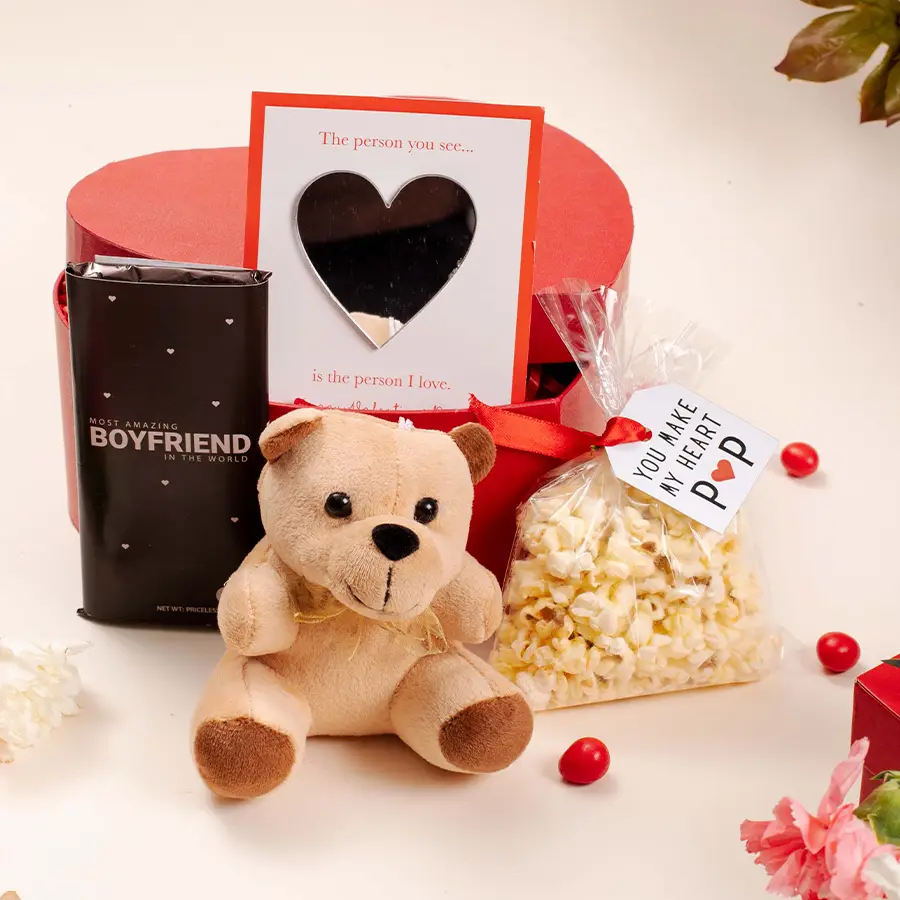 Heartfelt Surprises Gift Hamper featuring a teddy bear, heart-shaped mirror card, chocolate, popcorn pack, and confetti gift box.