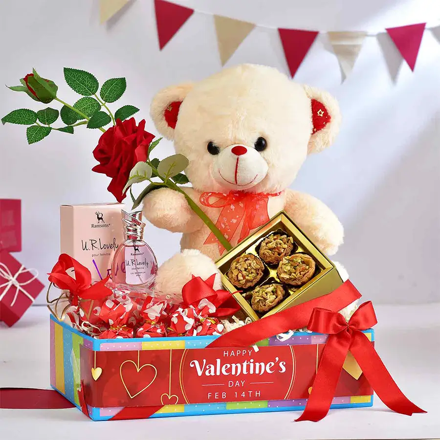 Romantic Elegance Bundle Hamper featuring a teddy bear, baklawa, heart-shaped chocolates, perfume, red rose, and a blue designer tray.