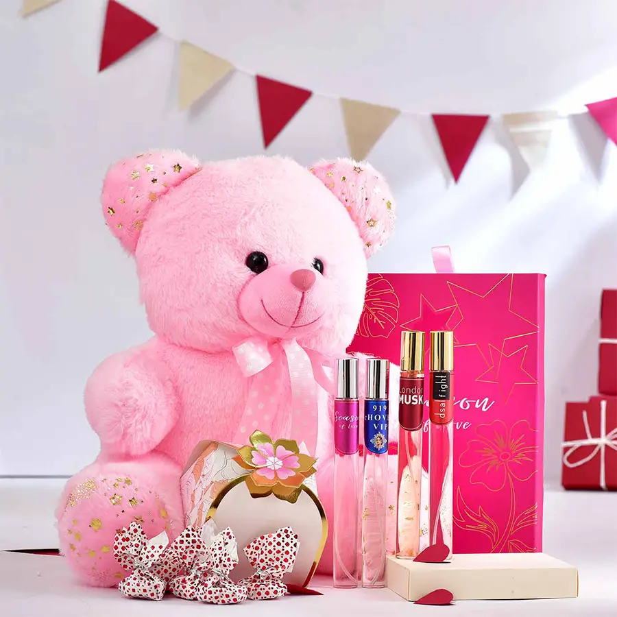 Ultimate Sweetheart Surprise hamper featuring a pink teddy bear, four perfume bottles, and a box of homemade chocolates
