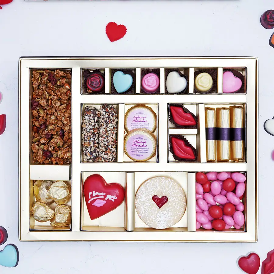 Assorted flavoured chocolates arranged in a decorative box with various shapes and colors including almond florantine, lip-shaped chocolates, and chocolate rockets