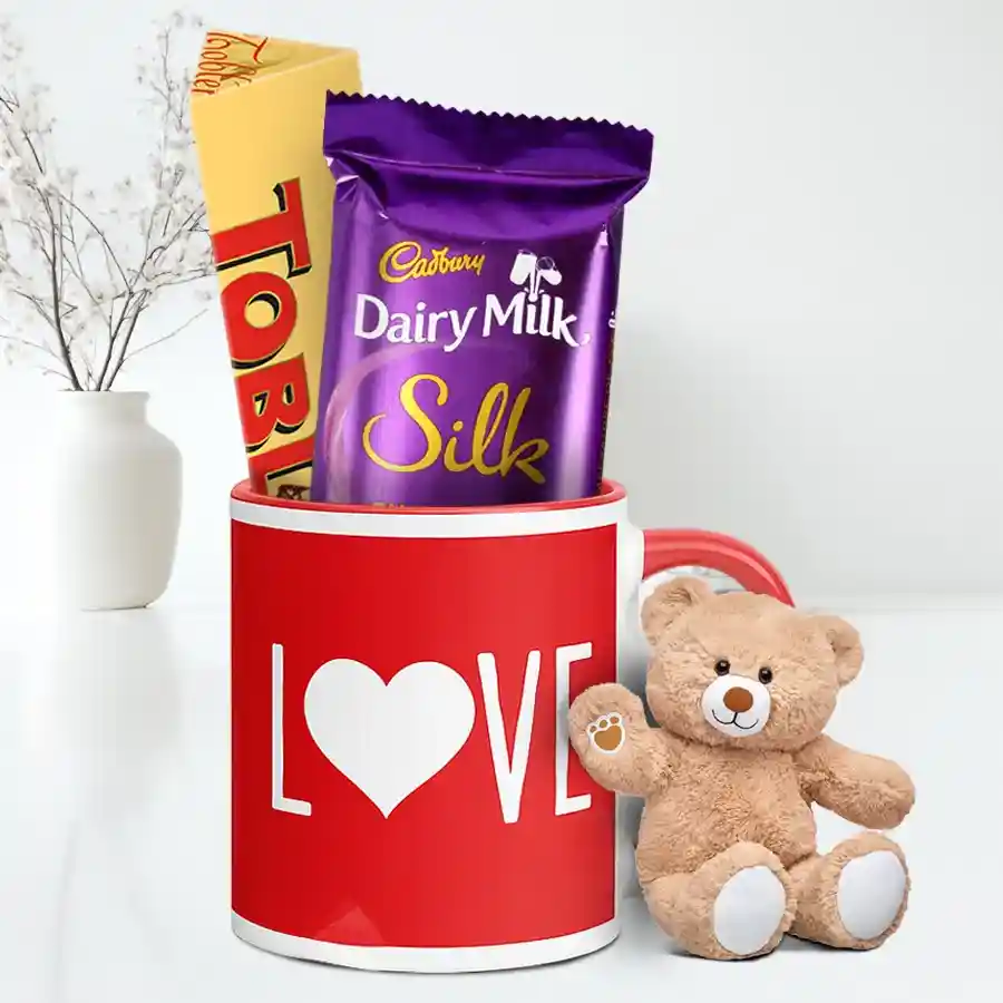 Heartwarming Valentine Surprises Hamper featuring a love-printed coffee mug, Toblerone and Cadbury Silk chocolates, and a cute teddy bear.