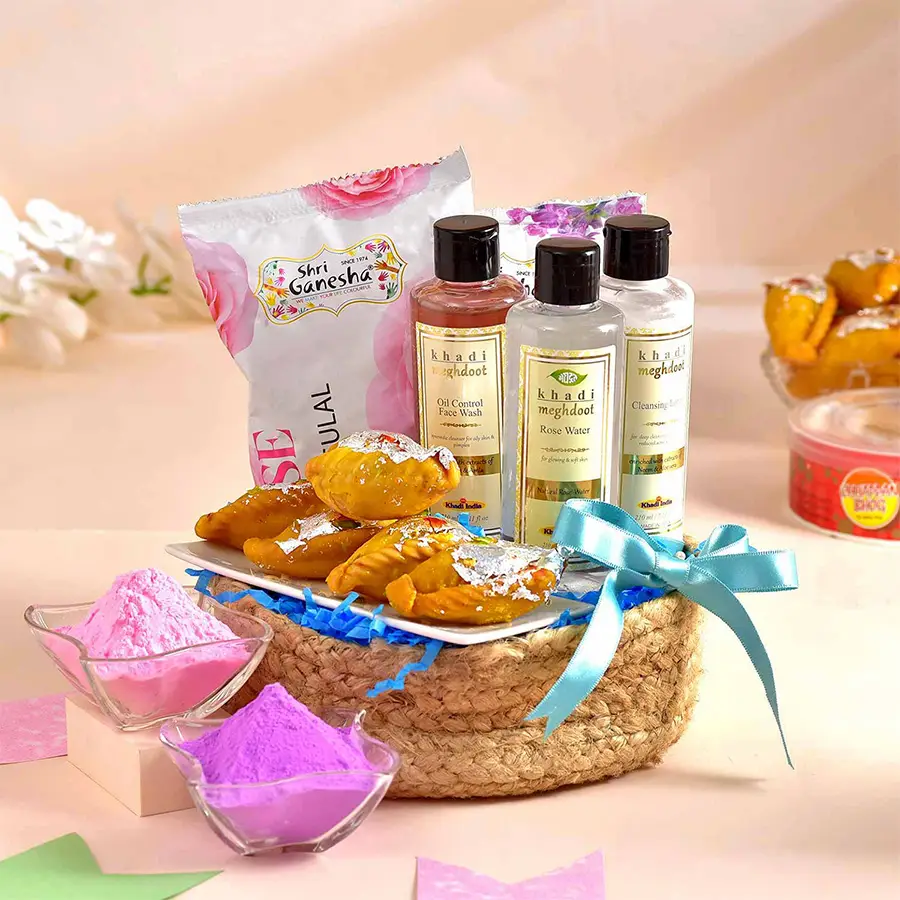 Holi Indulgence N Skincare Gift Hamper featuring a handmade jute basket filled with Chhappan Bhog Kesariya Gujiya, eco-friendly organic gulals, Khadi Meghdoot Oil Control Face Wash, Cleansing Lotion, and Rose Water