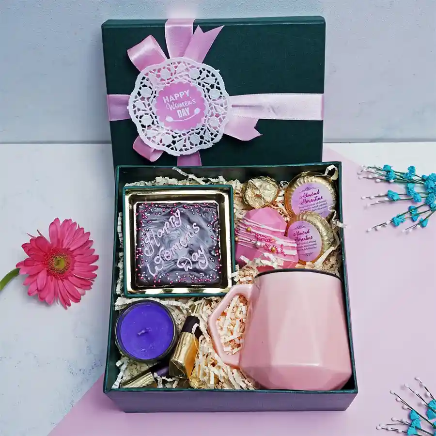 Women’s Delight Gift Box featuring assorted chocolates, chocochips cookies, almond florentines, masala-infused cranberries, a heart-shaped lollipop, a scented candle, and a charming cup, elegantly arranged for gifting.