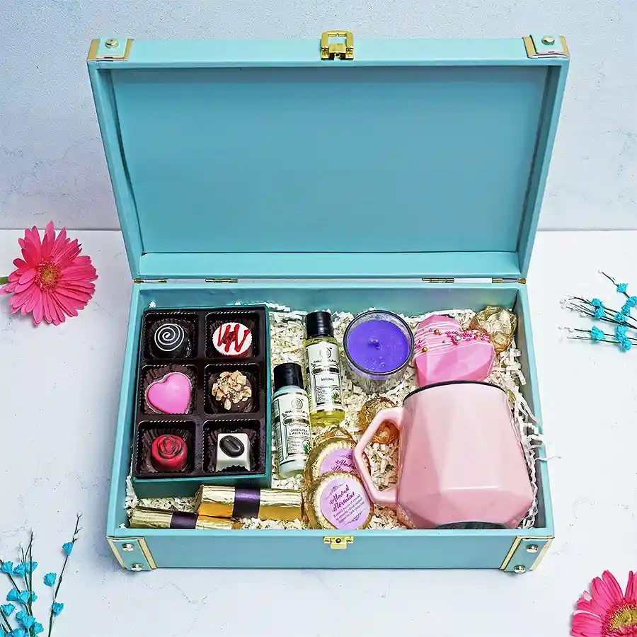 Delightful Women’s Day Surprise Trunk featuring chocolates, a scented candle, a heart-shaped piñata, a tea cup, herbal face wash, and a hair conditioner arranged thoughtfully in a decorative box