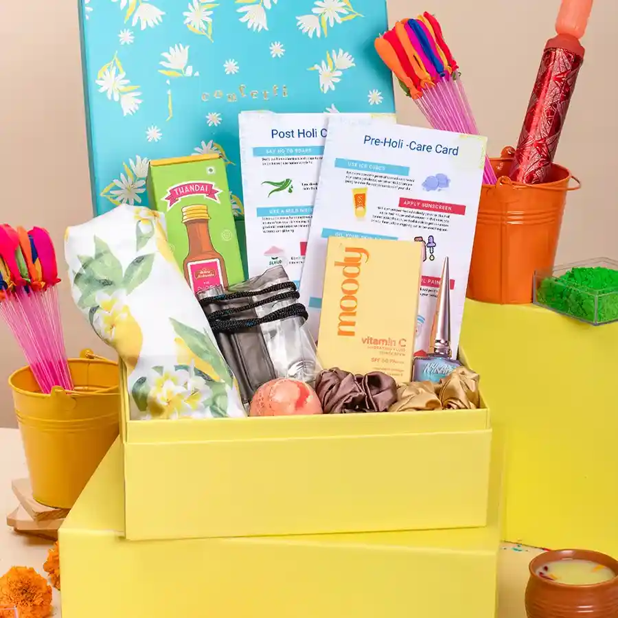 Holi Harmony Care Package featuring a cotton scarf, scrunchies, Nykaa nail polish, Moody Vitamin C Sunscreen, Phool Thandai, a waterproof phone case, a bath bomb, and care guides in a reusable box.
