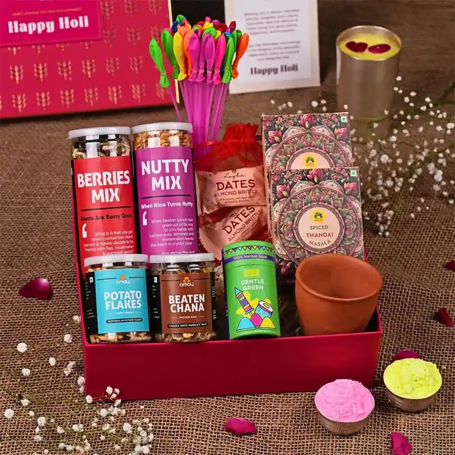 Vibrant Celebration Gift Box featuring an assortment of berries, nuts, potato flakes, protein-packed beaten chana, almond dates, instant thandai, a ceramic kullhad, colorful herbal gulaal, water balloons, and a Holi greeting card, all presented in a premium gold-foiled box.