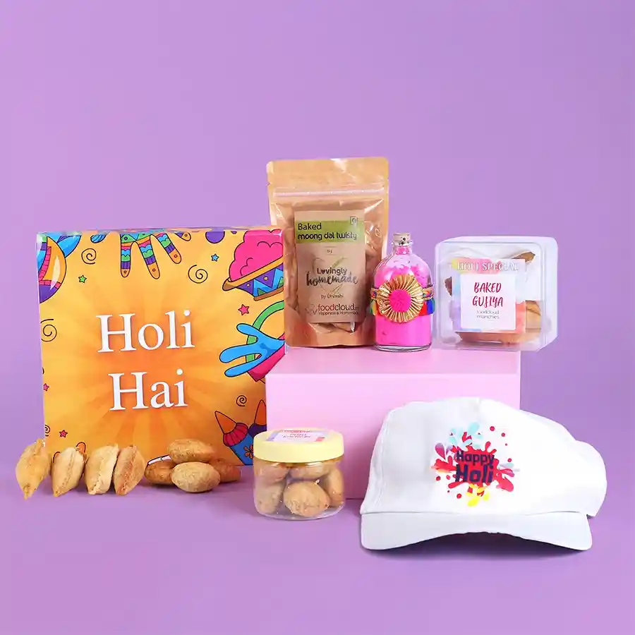 Colourful Delights Holi Hamper featuring baked moong dal twisties, mini kachoris, baked gujiyas, organic gulal, and a festive Holi cap.