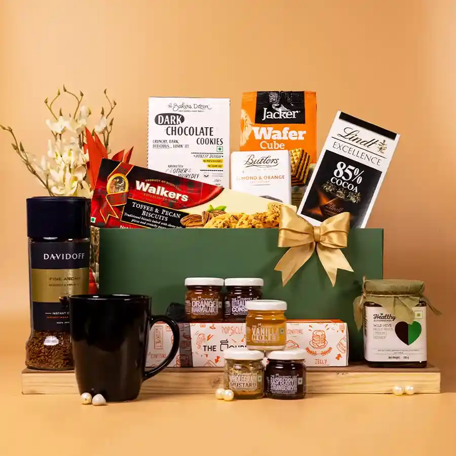 Delightful Gourmet Treats Assortment Hamper featuring Wild Basil Honey, dark chocolate bars, crunchy cookies, instant coffee, a black coffee mug, and a reusable basket