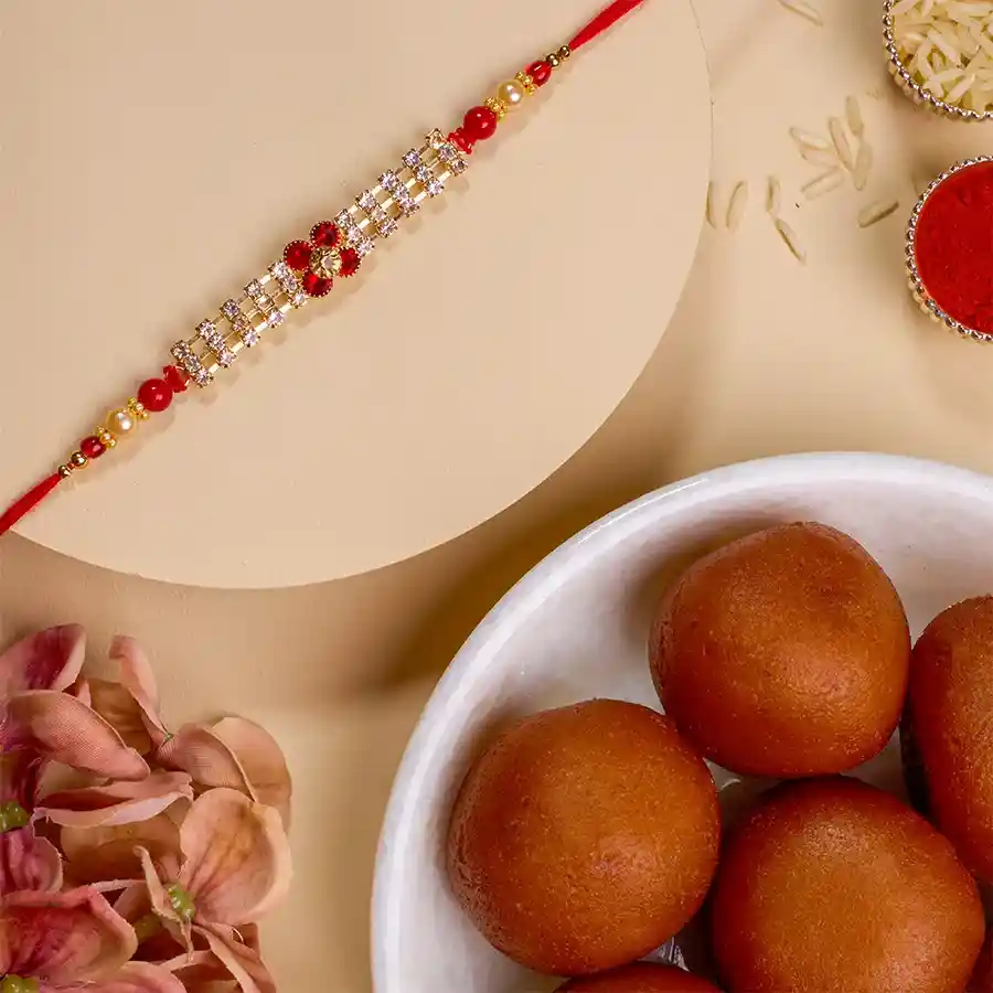 Delightful Rakhi and Gulab Jamun Combo with AD Rakhi, 500g box of Gulab Jamuns, Roli, Tilak, Chawal, and a message card.