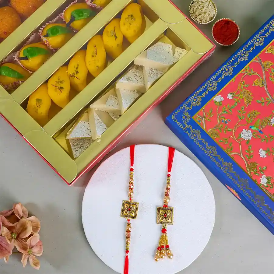 Sweet Moments Rakhi and Assorted Sweets Gift Set featuring a Kundan Bhaiya Bhabhi Rakhi, a 500g box of assorted sweets, roli tika, chawal, and a heartfelt message card.