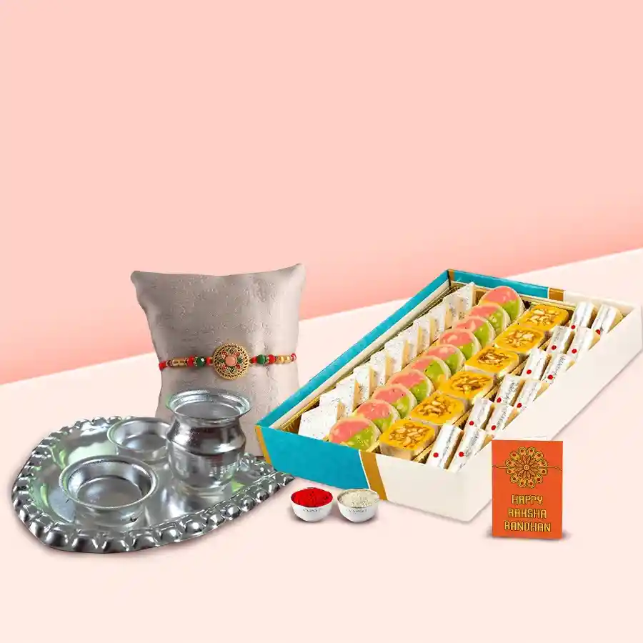Assorted sweets from Haldiram with a silver-plated paan-shaped Puja Aarti Thali, Rakhi, Roli, Tilak, and Chawal arranged for a festive celebration.