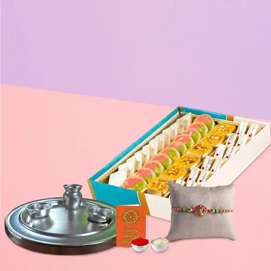 Haldiram's assorted sweets in a silver plated thali with a rakhi, roli, tilak, and chawal, beautifully arranged for Raksha Bandhan celebration.
