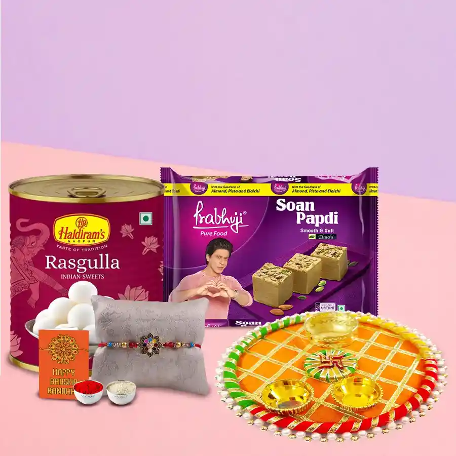 Thali Hamper featuring Haldirams sweets, including Rasgulla, Soan Papdi, and a decorative Rakhi with Roli, Tilak, and Chawal, elegantly arranged on a designer thali.