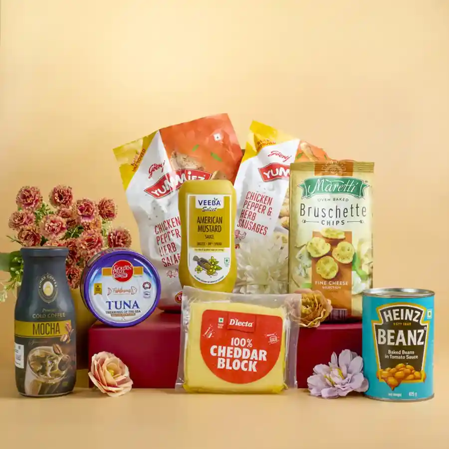 Deluxe Gourmet Savouries and Snacks Hamper with various gourmet food items including baked beans, bruschetta, cheddar cheese, mustard, cold coffee, tuna, chicken sausages, and salami arranged beautifully.