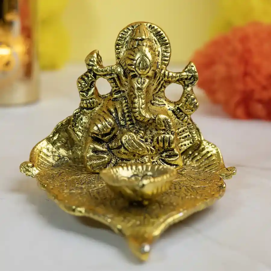 Brass Lord Ganesha idol on a crafted leaf with a diya, symbolizing abundance and harmony.