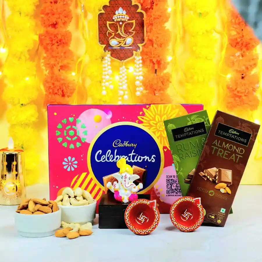 Delightful Ganesh Gift Set featuring a Mukut Ganesh idol, Cadbury Rum N Raisins, Almond Treats, Celebrations chocolate pack, two mud diyas, and 100g each of premium almonds and cashews.