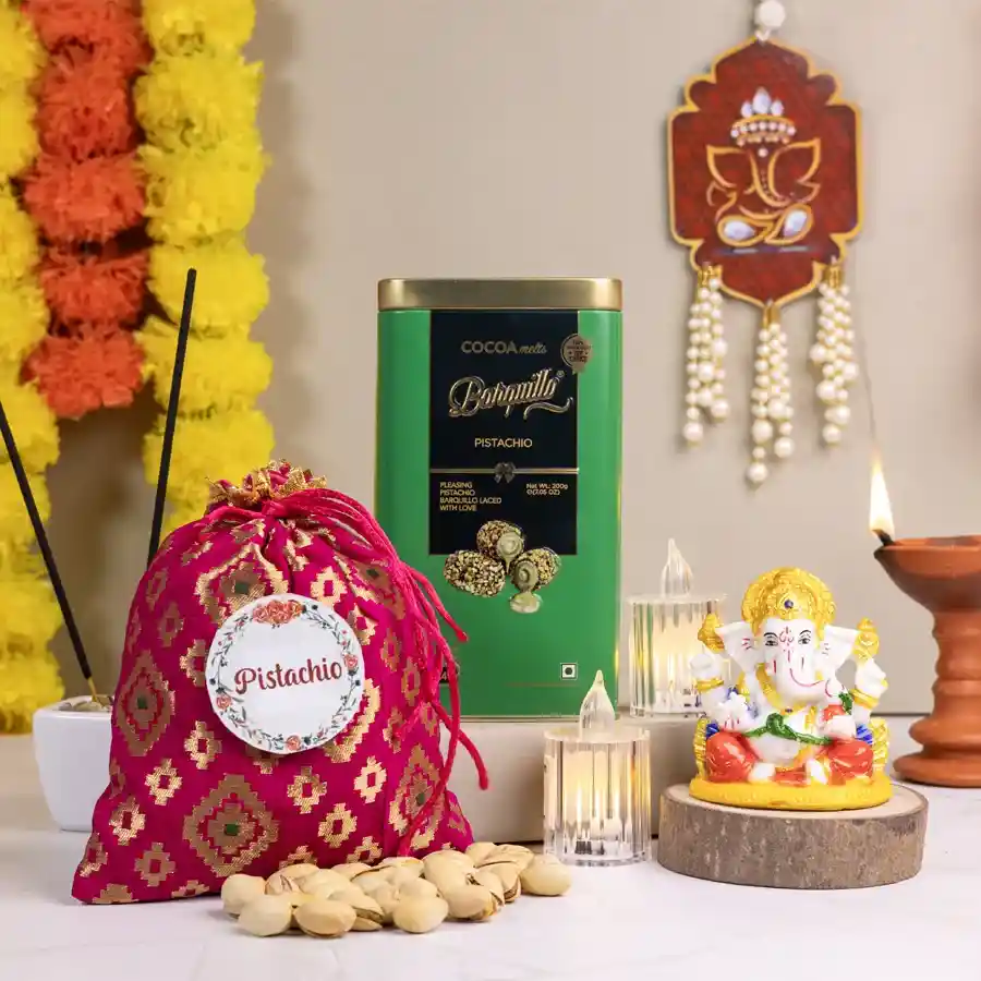 Festive Ganesha N Gifts Ensemble featuring a Marble Abhaya Mudra Ganesha, a 100g pistachio potli, 200g pistachio-coated Barquillo chocolates, and two LED tea lights arranged together.