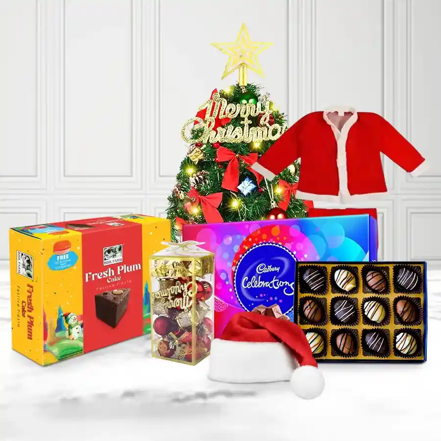 Graceful arrangement of Christmas gift items including a small tree, decorations, Santa suit, plum cake, chocolate pack, and handmade chocolates.