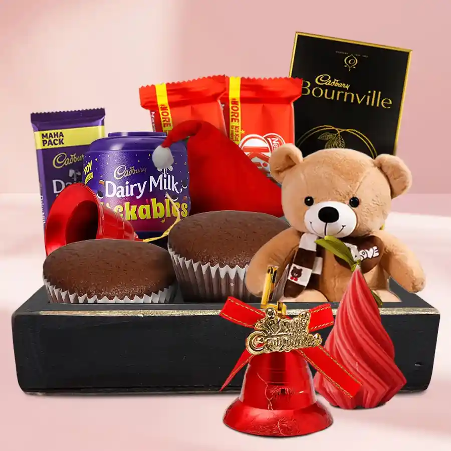 Little Basket of Joy Christmas Hamper filled with chocolates, a scented candle, a Santa cap, jingling bells, and a teddy bear.