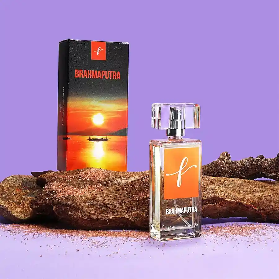 Bottle of Brahmaputra Perfume Crisp Waters Awakening with fresh citrus and floral notes, set against a serene riverbank background.