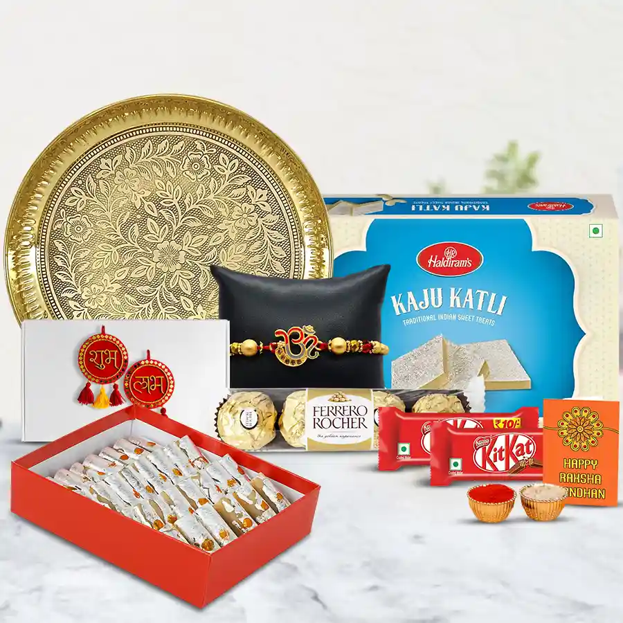 Exquisite Om Rakhi gift set featuring a designer Rakhi, golden Puja Thali, Ganesh decorations, Haldiram Kaju Katli, Kaju Pista, Ferrero Rocher, Nestle KitKats, Roli Chawal Tika, and a Rakhi wishes card.