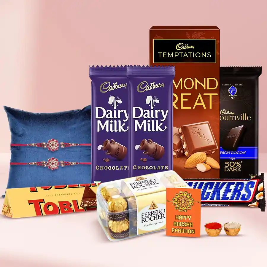 Festive hamper featuring a fancy Rakhi, assorted chocolates including Ferrero Rocher, Cadbury, Toblerone, and Snickers, along with Roli, Tilak, and Chawal, arranged beautifully for Raksha Bandhan celebration.