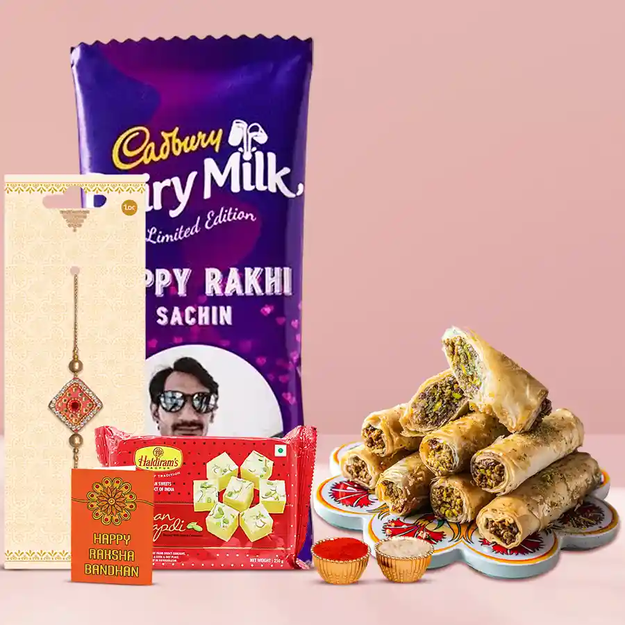 Rakhi with personalized chocolate treat, featuring a customized photo Cadbury Silk, a Roll Baklawa box, and a premium Rakhi, alongside free Rakhi, Roli, Tilak, and Chawal.