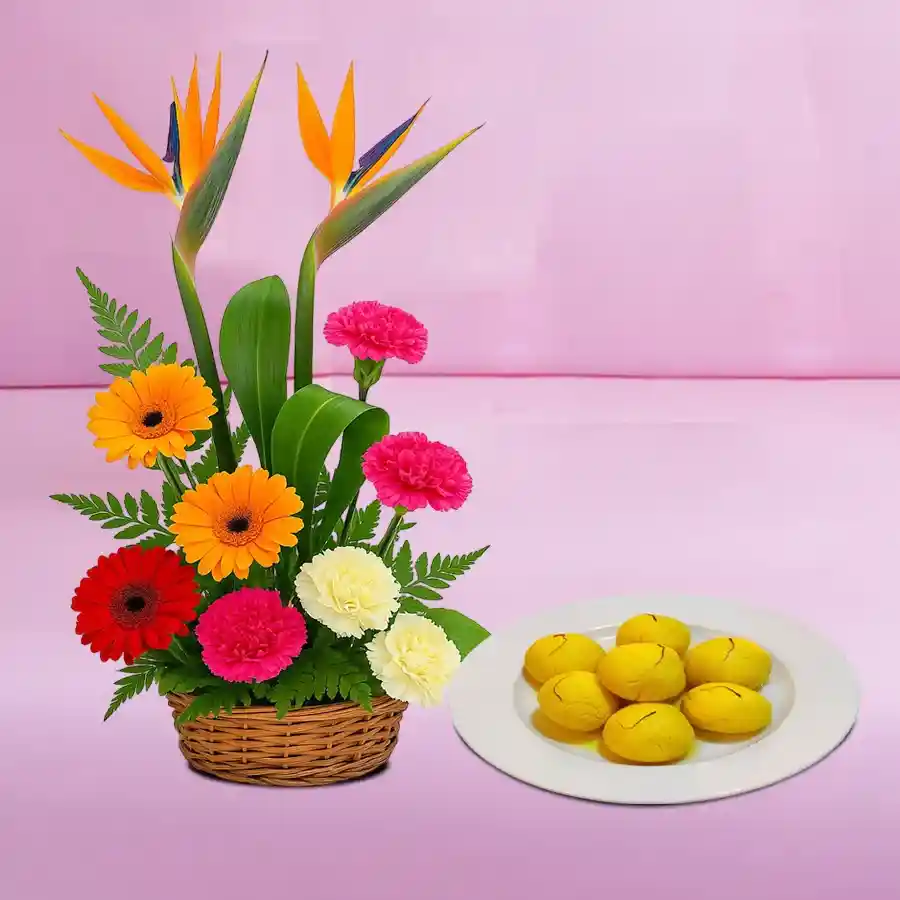 Vibrant flower arrangement with Gerberas, Carnations, and Birds of Paradise, alongside Raj Bhog sweets.
