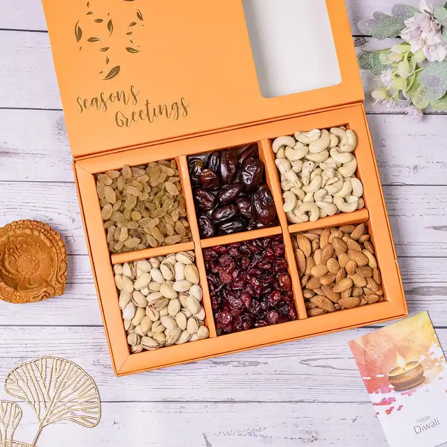 Assorted nuts in a decorative gift box with a traditional mud diya on top