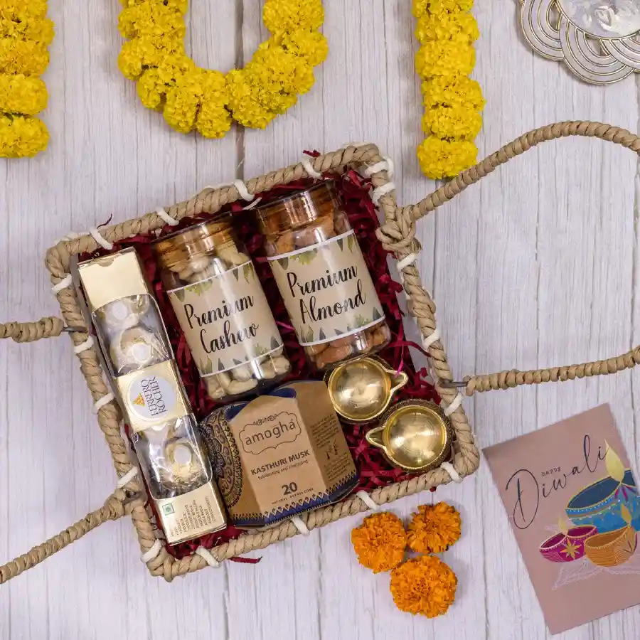 Elegant Festivity hamper featuring premium cashews, almonds, Ferrero Rocher chocolates, Amogha incense cones, and brass diyas in a designer handle basket.